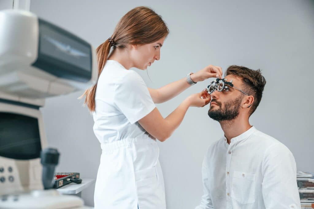 Optometric device. Man's vision checked by female doctor in the clinic